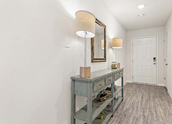 Entryway with blue console table, lamps, mirror, and wood-look flooring.