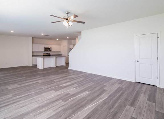 an empty living room and kitchen with a ceiling fan