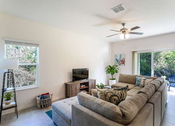 Bright living room with sectional sofa, TV, and sliding glass doors to patio.