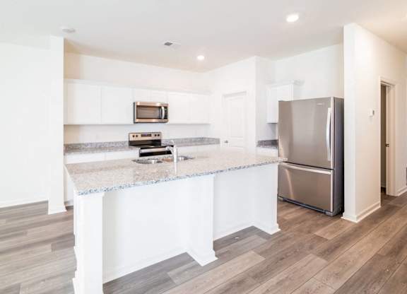 a kitchen with a marble counter top and a stainless steel refrigerator