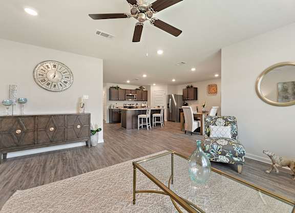Open-concept living and kitchen area with wood floors, neutral walls, and stylish decor.