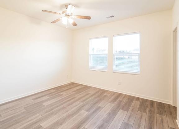 an empty living room with wood floors and a ceiling fan