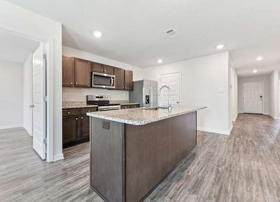 Modern kitchen with granite countertops, stainless steel appliances, and wood-look flooring.