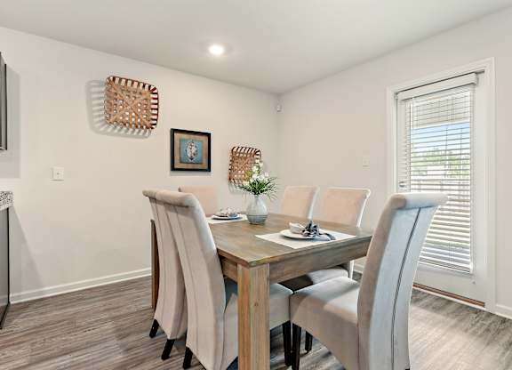 Dining room with wooden table, six upholstered chairs, and decorative wall baskets.