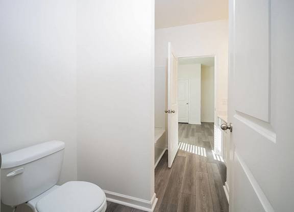 a white bathroom with a toilet and a hallway