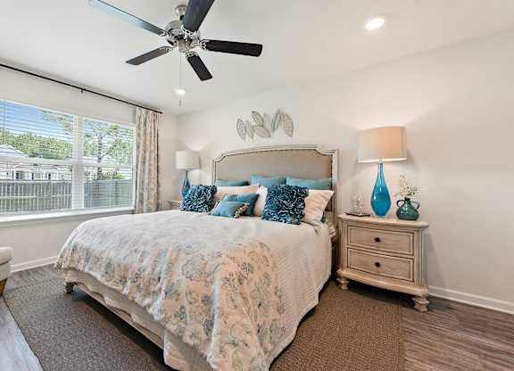 Comfortable bedroom with a large bed, blue accents, and a ceiling fan.