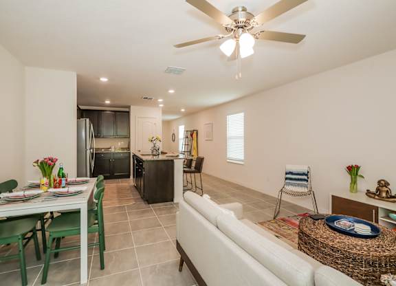 Open-concept living room and kitchen with dining table, island, and neutral decor.