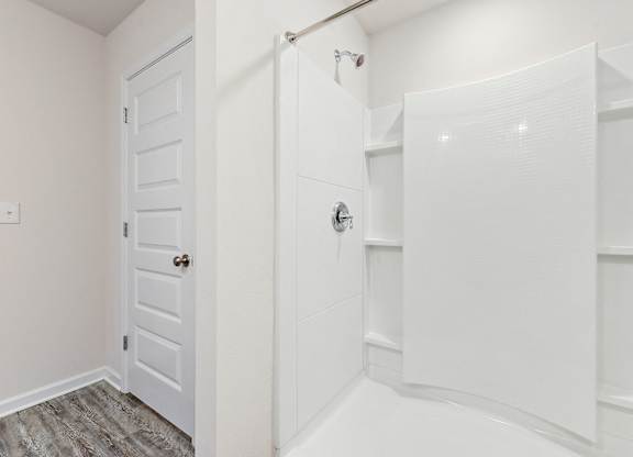 Bright white bathroom with a shower stall and a paneled door.