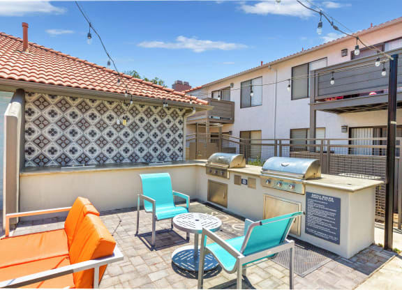 a patio with a barbecue grill and a table with chairs