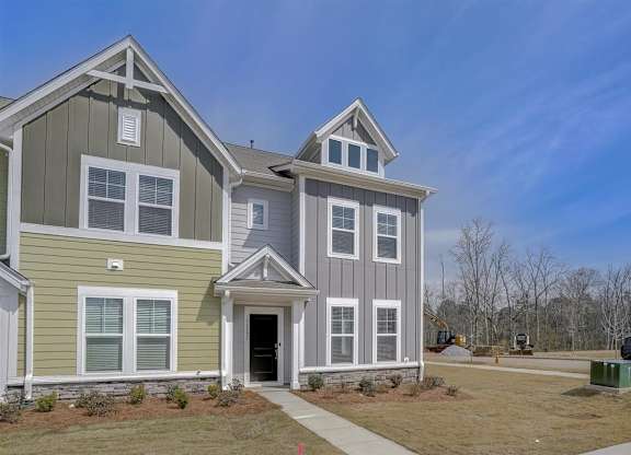 A two-story house with a green and grey exterior.