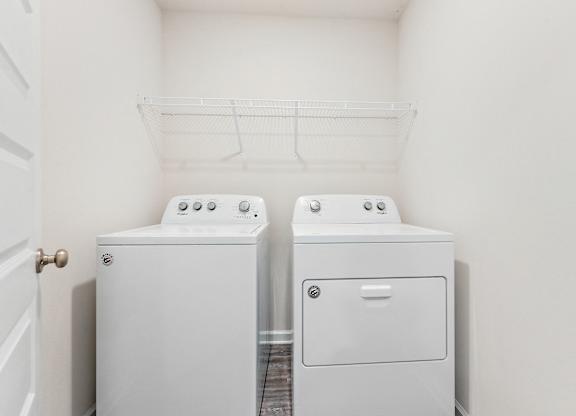 White Whirlpool washer and dryer in a laundry room with wire shelving.