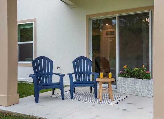 Blue Adirondack chairs on a porch with orange juice.