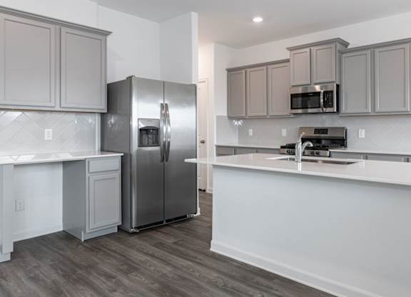 Humble, TX Apartments for Rent - Edgewater at the Lagoon - Kitchen with Stainless Steel Appliances, Gray Cabinetry, Large Kitchen Island, Quartz Countertops, and Hardwood Floor.