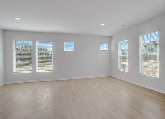 A large empty room with wooden floors and windows.