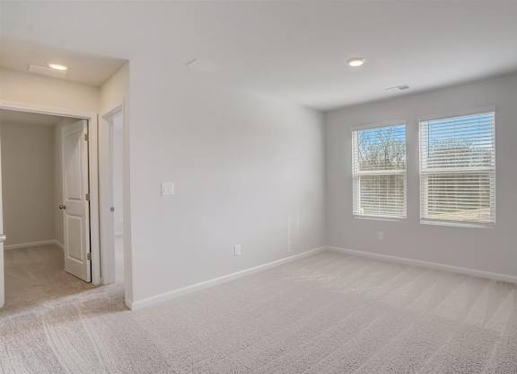 A room with a carpeted floor and a window with blinds.