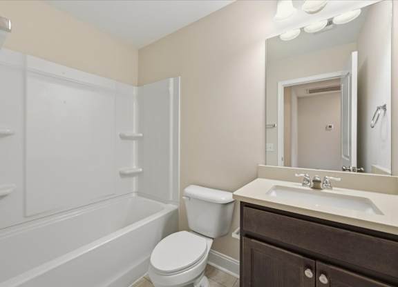 A white toilet sits next to a white bathtub in a bathroom.