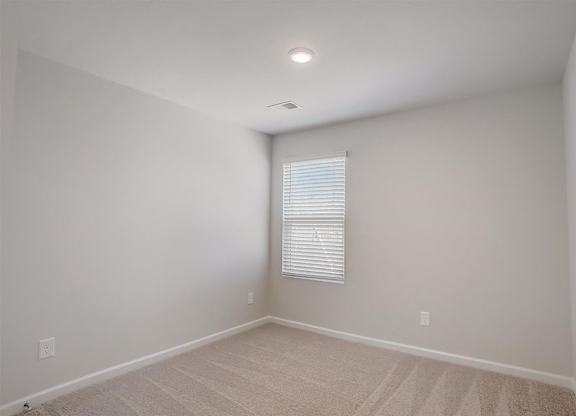 A room with a window covered by blinds and a carpet on the floor.