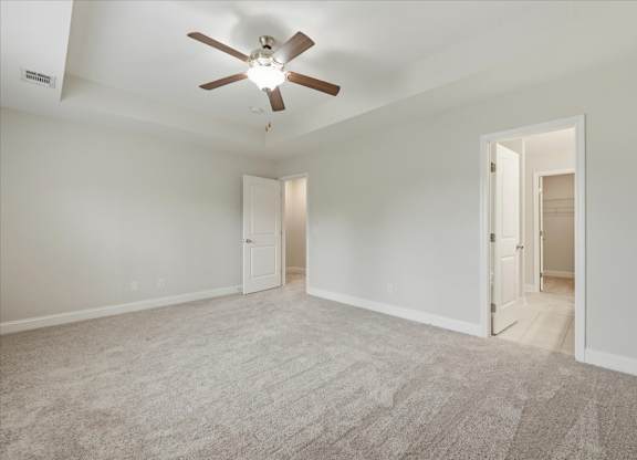 A room with a ceiling fan and carpeted floor.