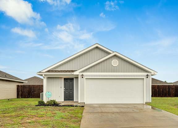 A house with a grey garage door and a green sign in front.