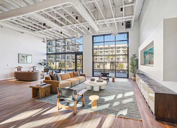 A living room with a large window and a view of a building outside.