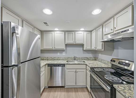 A modern kitchen with a stainless steel refrigerator and a granite countertop.