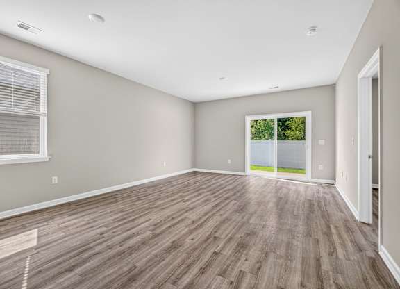 A room with wooden flooring and a window with blinds.
