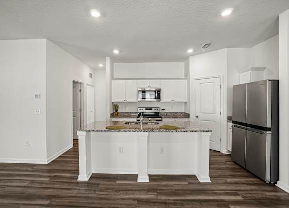 A kitchen with white cabinets and a granite countertop.