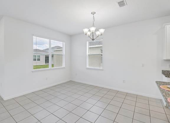 A room with white walls and a tiled floor with a chandelier hanging from the ceiling.