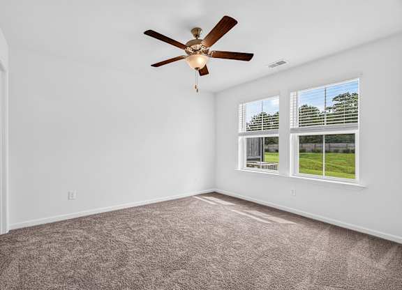 A room with a ceiling fan and carpeted floor.