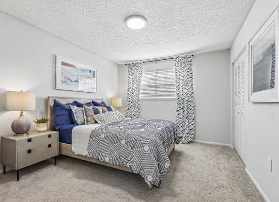 A bedroom with a bed, nightstand, and a painting on the wall.