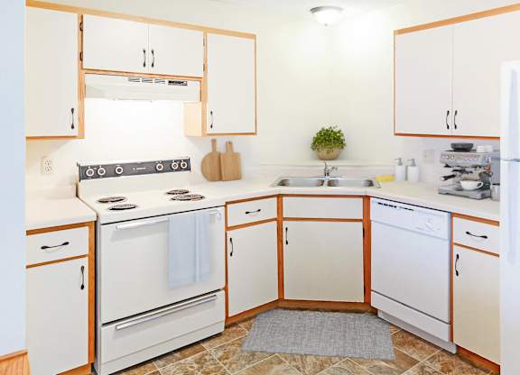 A kitchen with white appliances and wooden cabinets.