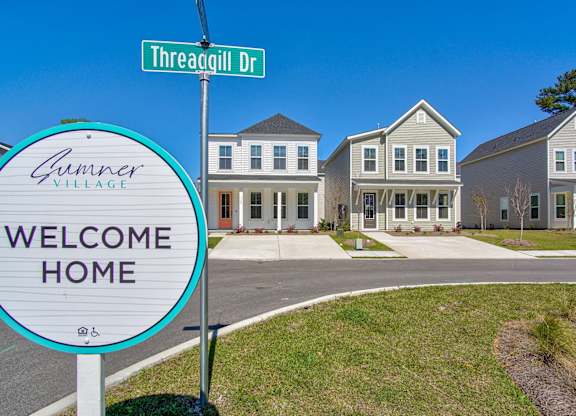 Houses for Rent in North Charleston, SC - Sumner Village - Street View of Apartment Homes with Driveways, Sidewalk, Manicured Lawns, and Property Signage.