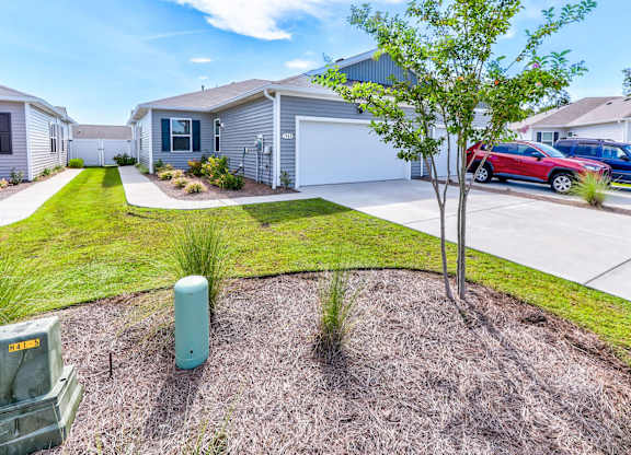 a house with a driveway and a tree in front of it