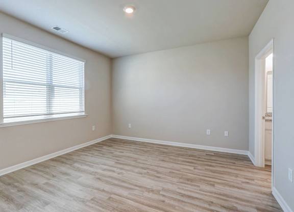 an empty living room with wood flooring and a window