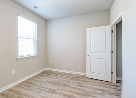 an empty room with a white door and a window
