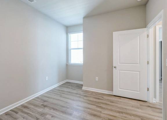 an empty room with a white door and a window