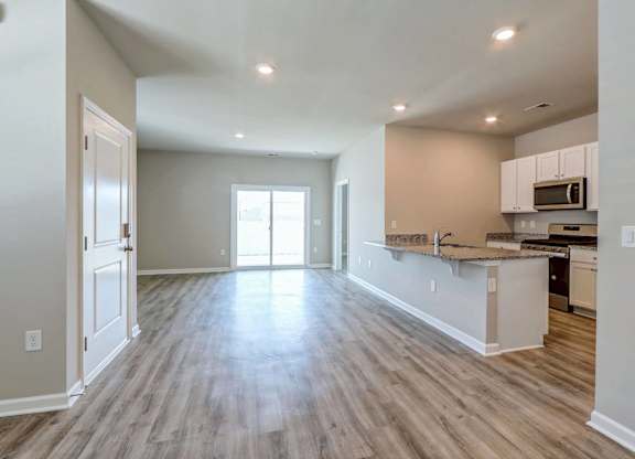 an empty living room with a kitchen with a counter top