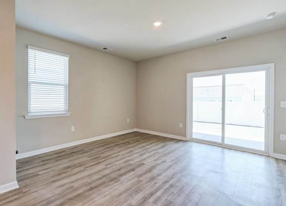 an empty living room with wood floors and a glass door