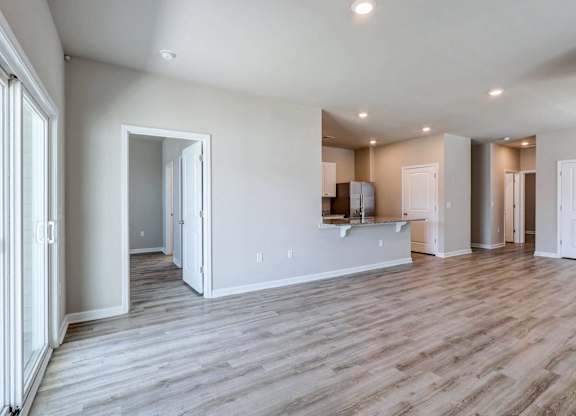 the living room and kitchen of a new home with white walls and wood flooring