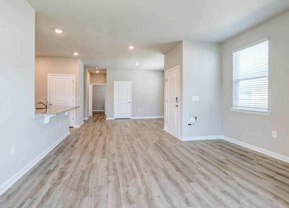 a spacious living room with a hard wood floor and white walls