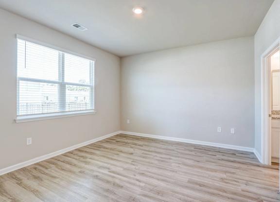 an empty living room with wood flooring and a window