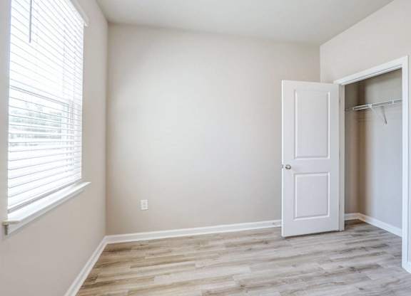 an empty bedroom with a closet and a window