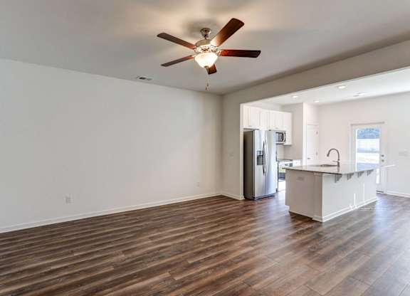 Townhomes near Tanger Outlets in North Charleston, NC - Highland Townhomes - Living Room with High Ceiling, Ceiling Fan, Wood-Style Flooring, and Access to the Kitchen.
