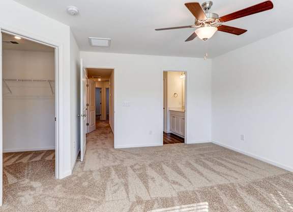 an empty living room with a ceiling fan and a closet