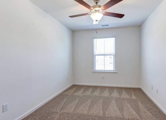 an empty room with a ceiling fan and a window