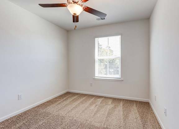 an empty room with a ceiling fan and a window