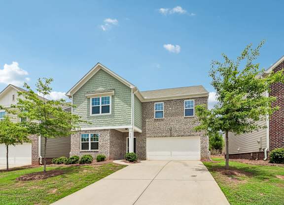 A house with a garage and a driveway in front.