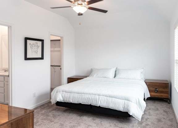 Three-Bedroom Homes for Rent in Humble, TX - Edgewater at the Lagoon - Bedroom with Plush Carpeting, a Large Window, a Ceiling Fan, a Closet, and a Bathroom