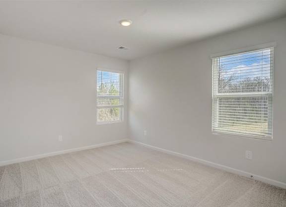 A room with two windows and a carpeted floor.