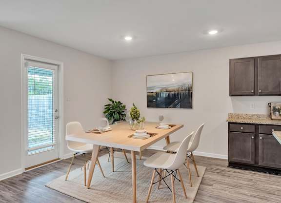 A dining room with a table set for two and a painting on the wall.